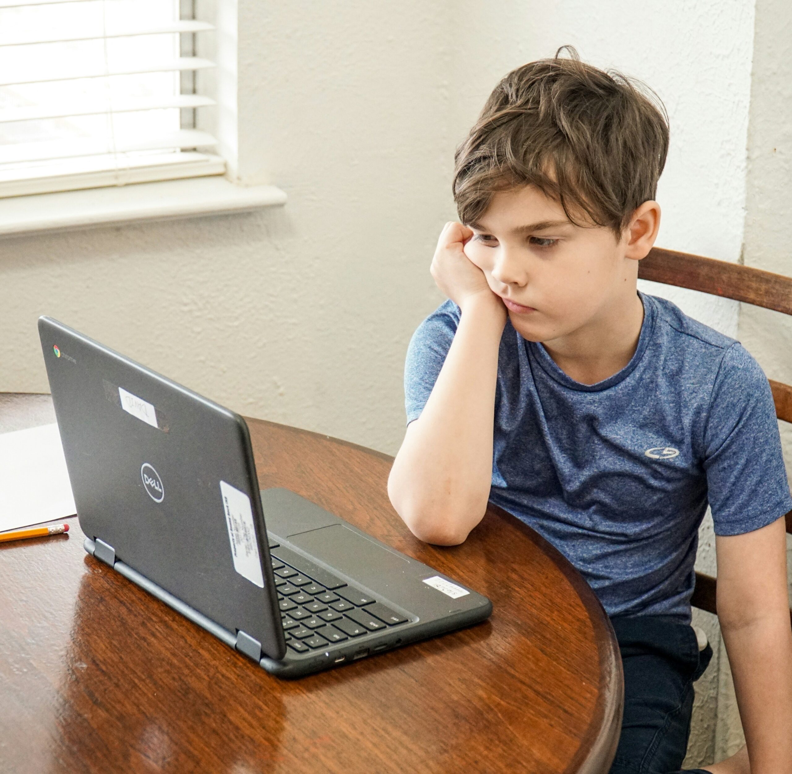 A young boy, looking unhappily at his laptop