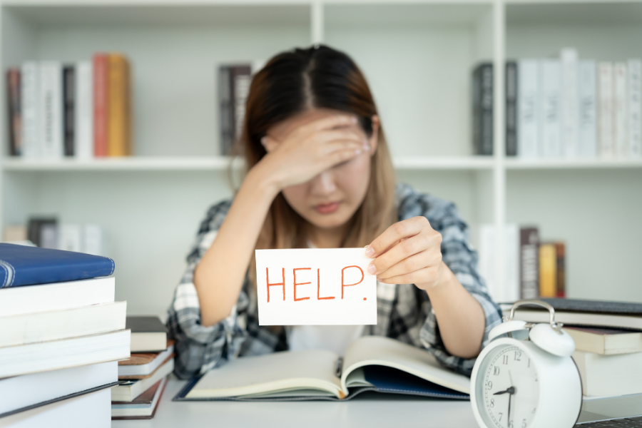 Person looking overwhelmed, holding up a sticky note saying "help"